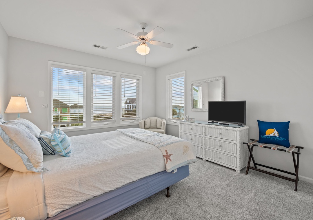 Drift off to sleep in your coastal-themed bedroom with ocean views through bright windows, complete with TV for your comfort.