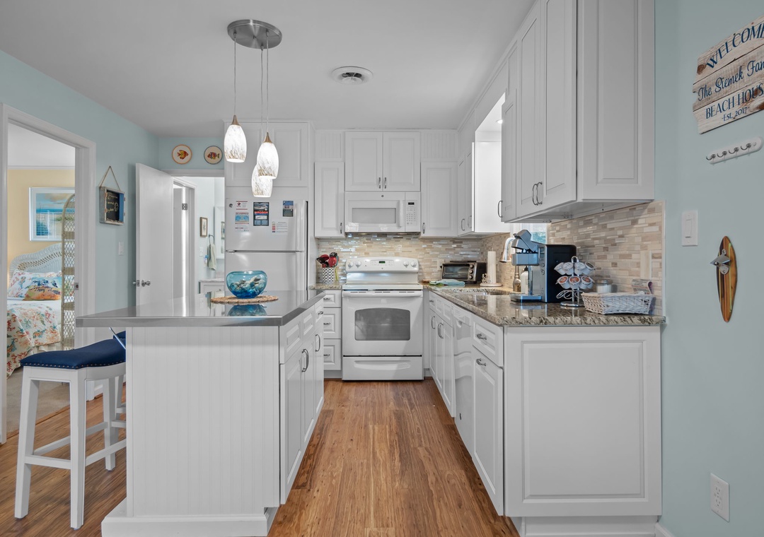 Your coastal-inspired kitchen invites you to prepare meals surrounded by soothing sea glass walls and pristine white cabinetry, complete with modern appliances.