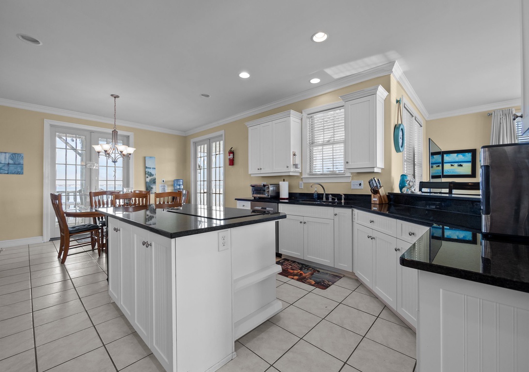 Your spacious kitchen invites culinary adventures with its gleaming granite countertops, bright white cabinets, and modern black appliances.