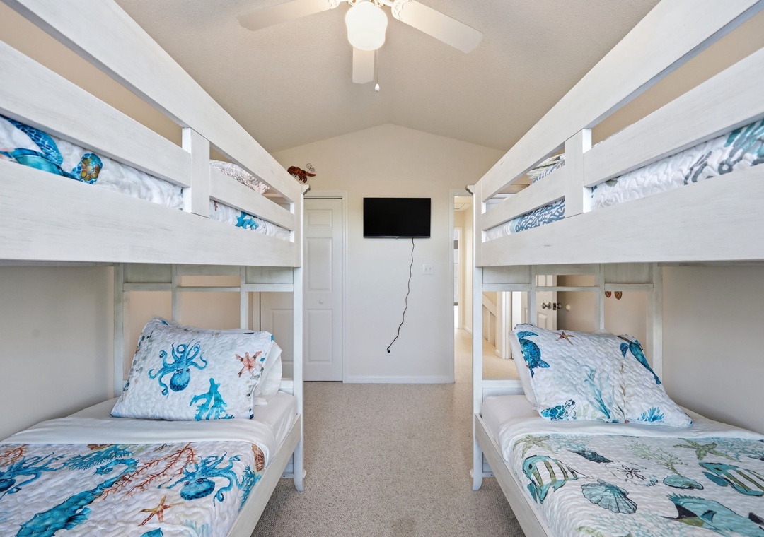 Four cozy bunk beds with ocean-themed bedding create the perfect sleep space for kids or groups, with a wall-mounted TV for movie nights together.