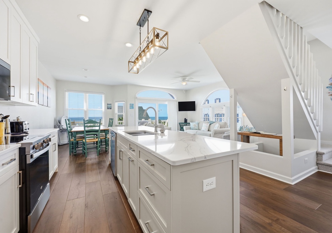 Your open-concept living space flows seamlessly from a chef's kitchen with marble countertops to a bright living area, all framed by stunning ocean views through arched windows.