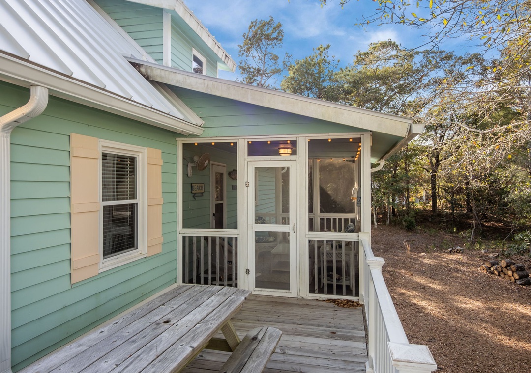 Charming coastal cottage with screened porch surrounded by mature trees in a peaceful wooded setting.