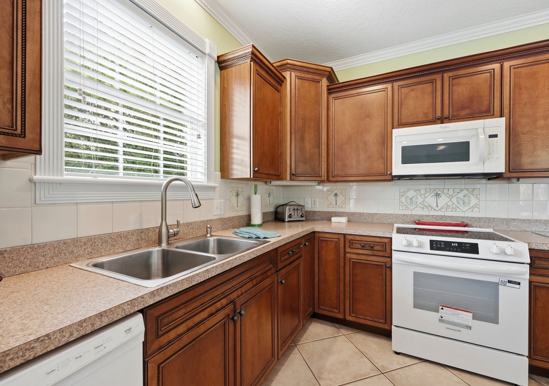 Cook up your vacation favorites in this fully equipped kitchen with rich cabinetry, modern appliances, and plenty of counter space for meal prep. Natural light streams through the window, making your cooking experience bright and enjoyable.