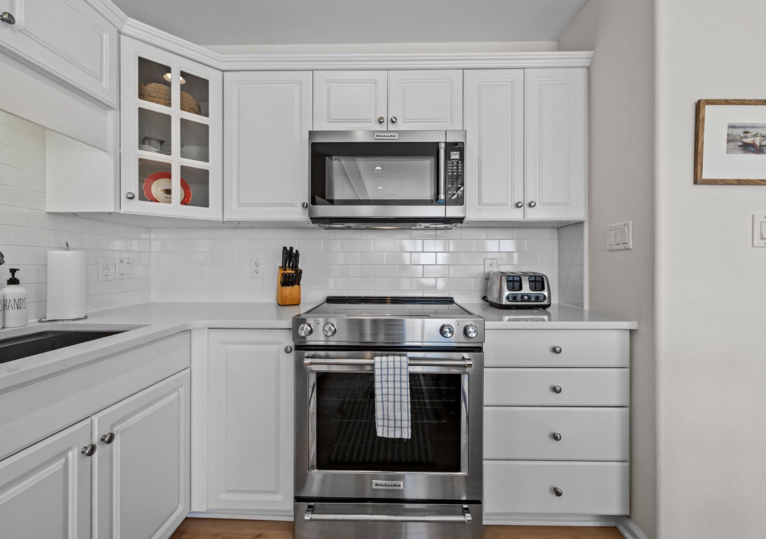 Cook your favorite meals in this bright, fully-equipped kitchen with stainless steel appliances and classic white cabinetry.
