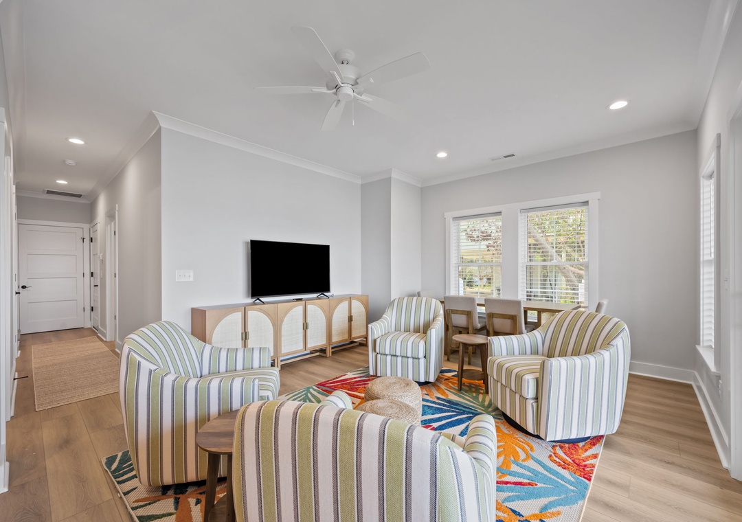 Relax in your stylish living space with comfortable striped seating and bright natural light streaming through large windows.