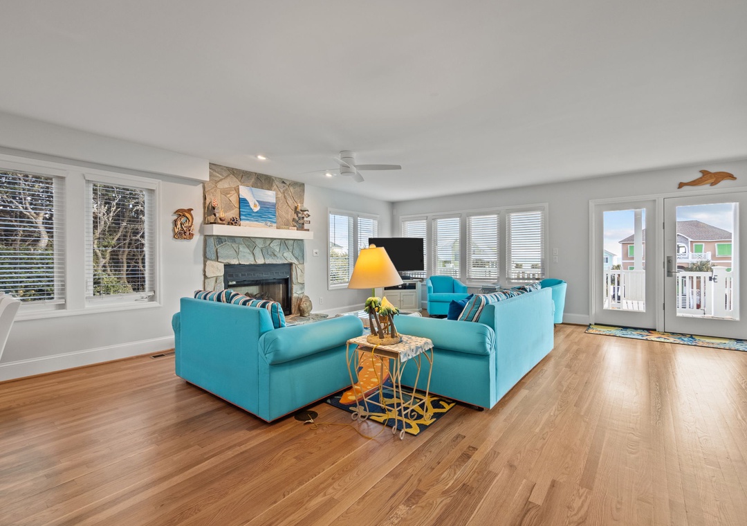 Sink into plush turquoise seating while warm hardwood floors stretch beneath your feet in this bright, coastal-inspired living room.