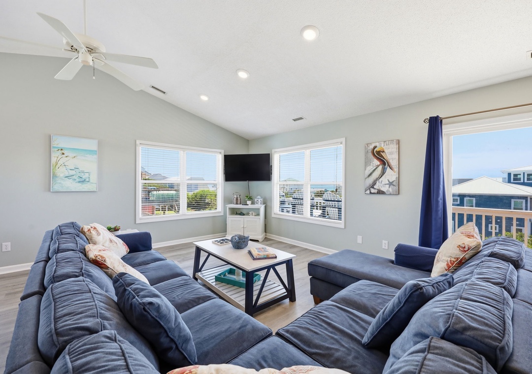 Unwind in your bright living space with plush seating, coastal art, and large windows framing stunning water and neighborhood views. Perfect for gathering after a beach day.
