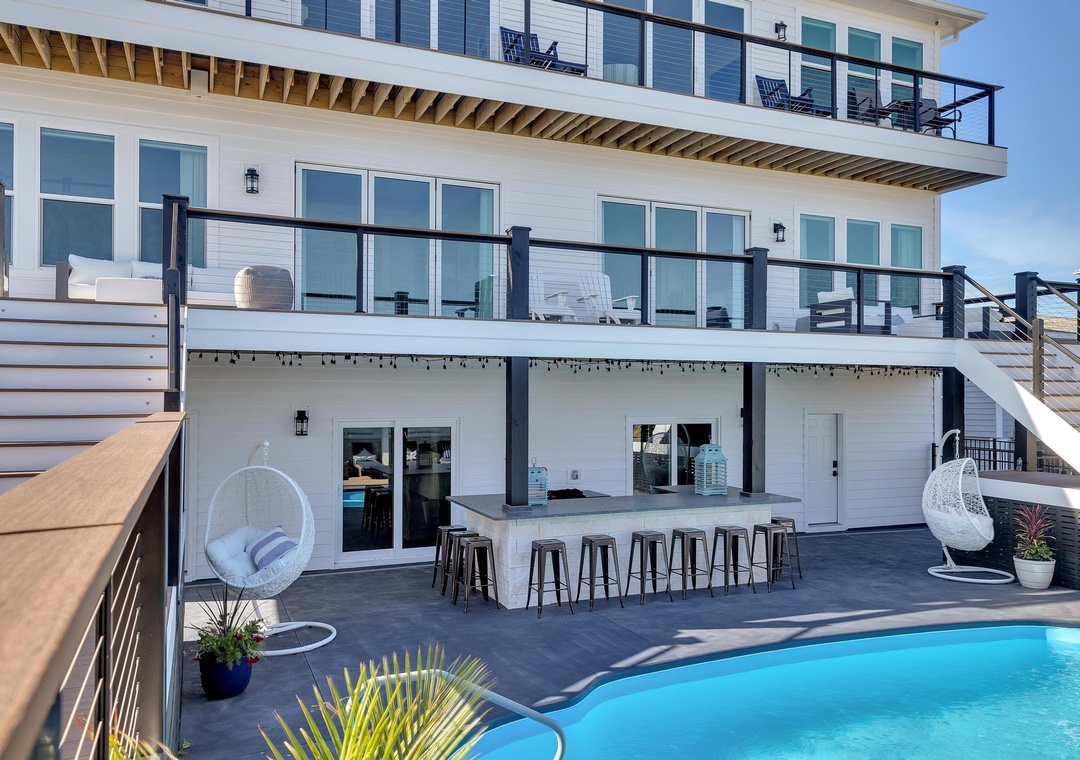 This multi-level beachfront property features expansive balconies, a sparkling pool, and an outdoor bar—perfect for your ultimate coastal getaway with friends and family.