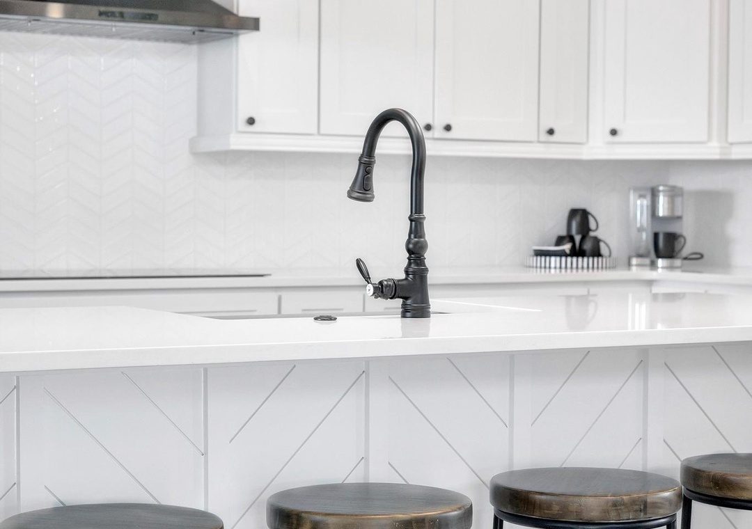 Gather at the sleek island under modern pendant lights. White cabinetry and clean countertops give you a bright, open space to whip up meals or sip morning coffee.