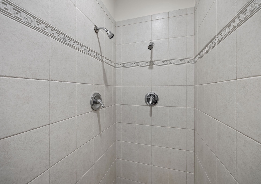 Step into your private dual-head shower sanctuary with elegant tiled walls and chrome fixtures for a refreshing start to each day.