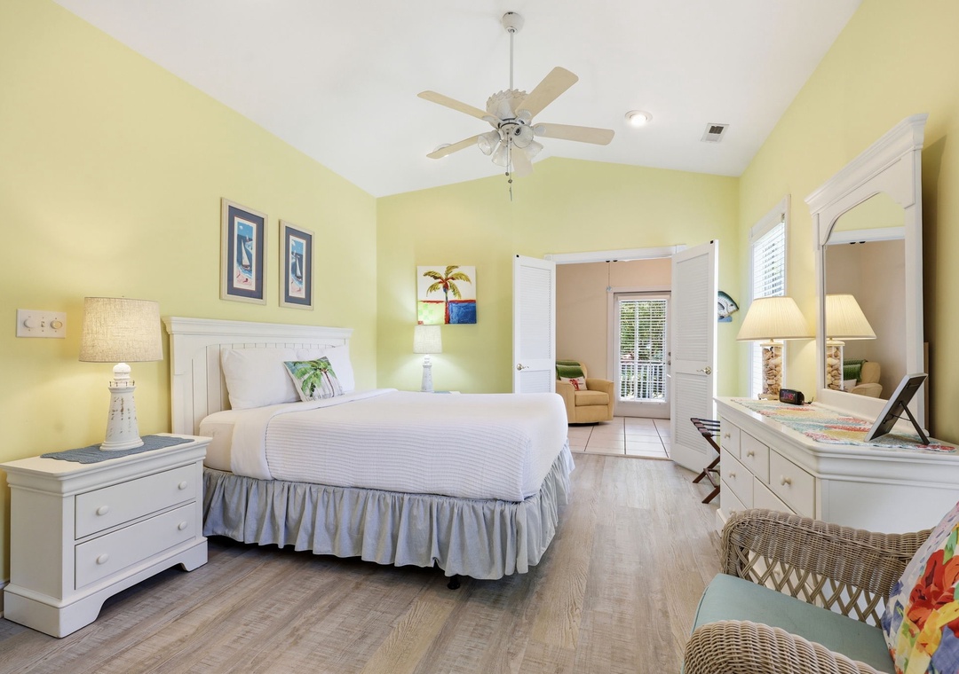Relax in this sunny, coastal-inspired bedroom where crisp white linens, tropical touches, and soft yellow walls create your peaceful retreat after a day of exploring.
