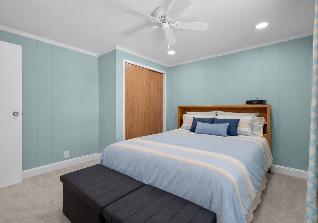 Drift off to sleep in your peaceful bedroom with calming seafoam walls, crisp linens, and a ceiling fan for cool comfort.