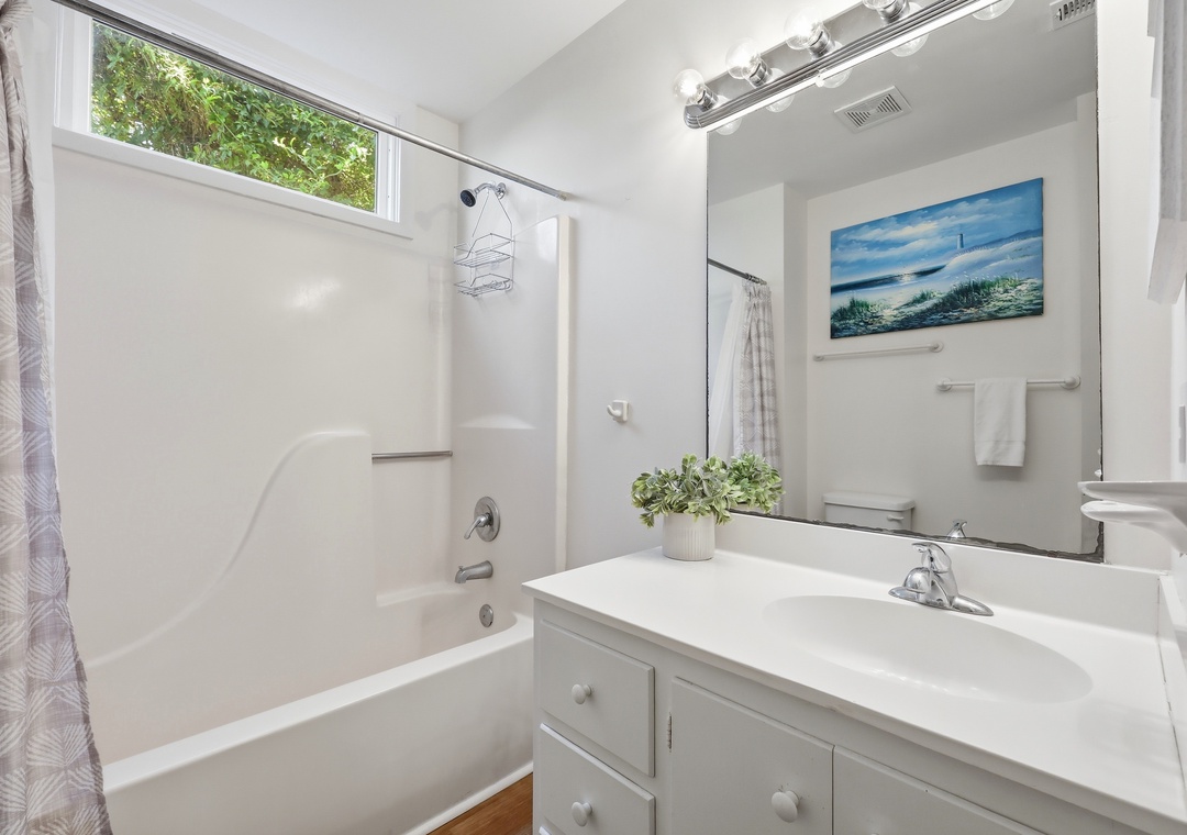 Freshen up in your bright, clean bathroom with a deep soaking tub, fresh towels, and serene coastal artwork to help you unwind after a day of exploring.