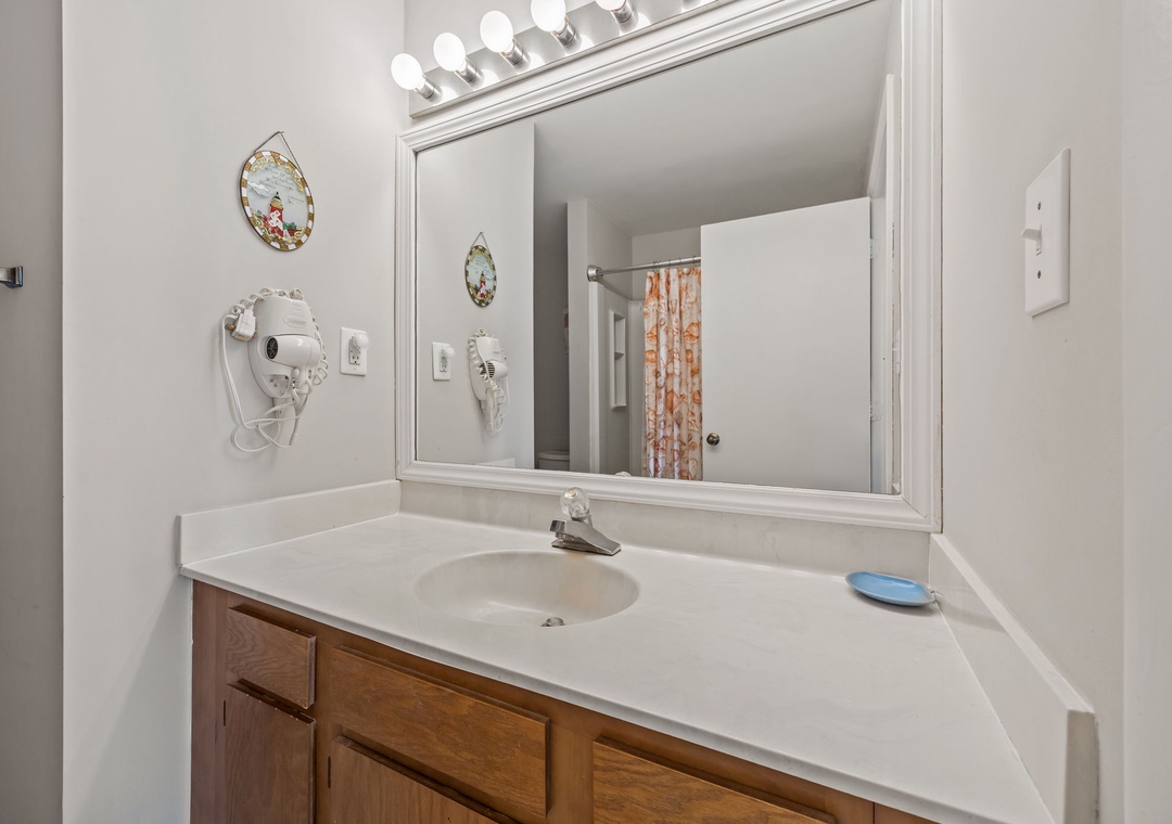 Your private bathroom features bright vanity lighting and convenient amenities including a hair dryer for your comfort.