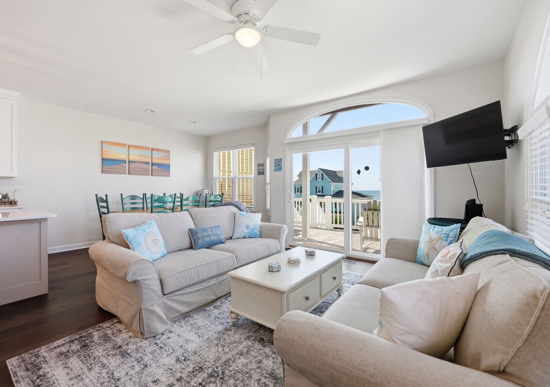Relax in this bright coastal living space with soft seating, coastal accents, and a ceiling fan. Glass doors open to your private balcony with outdoor views.