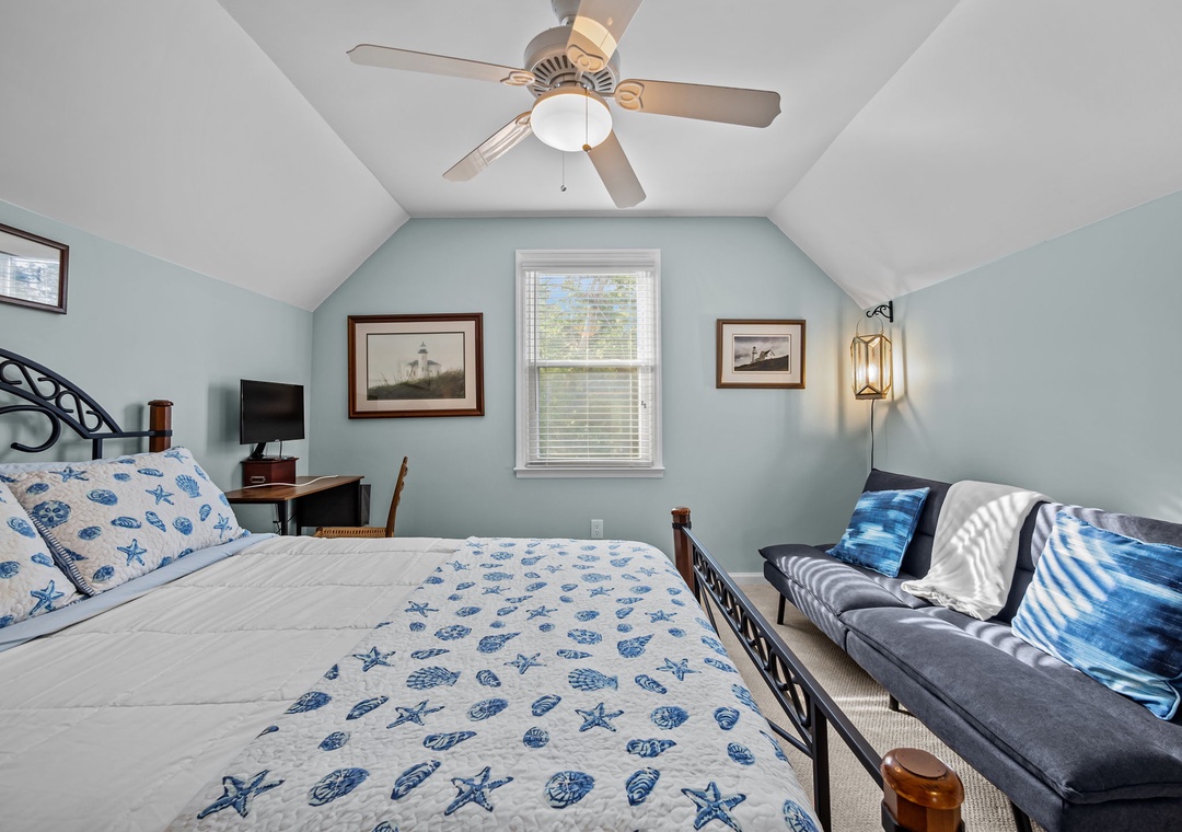 Your coastal-themed bedroom features nautical linens, vaulted ceilings with ceiling fan, and comfy seating area for relaxing after beach days.