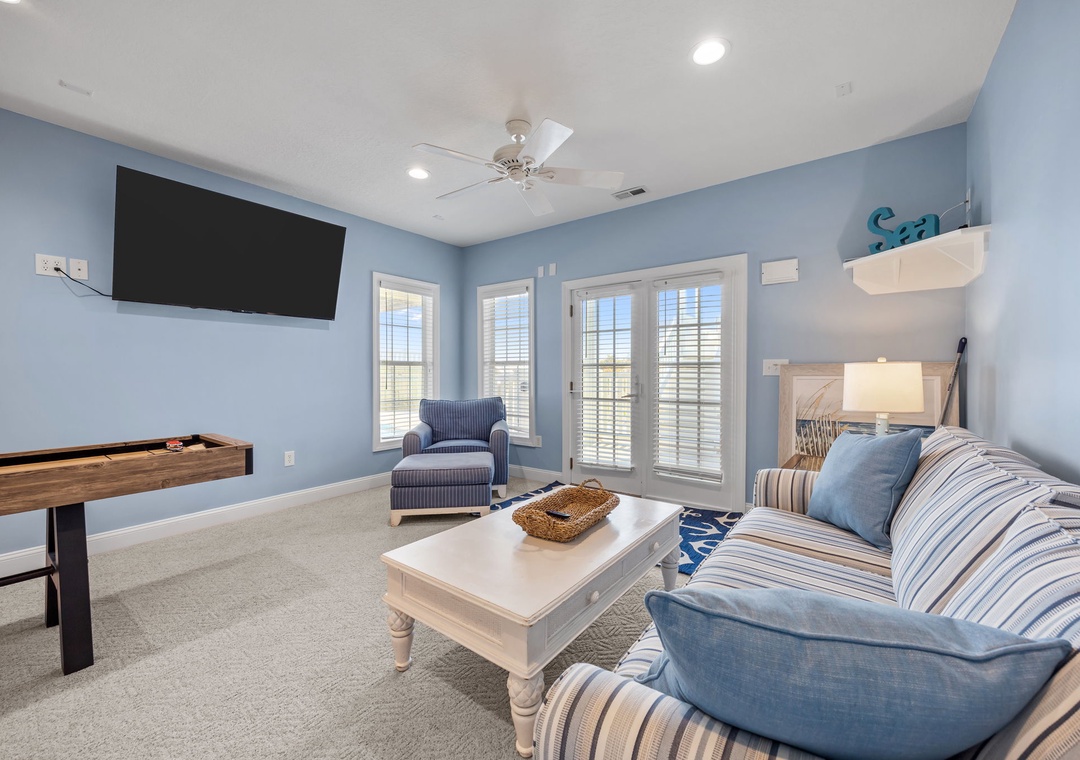 Relax in your serene blue living room with coastal charm, complete with comfortable seating, entertainment, and peaceful garden views.