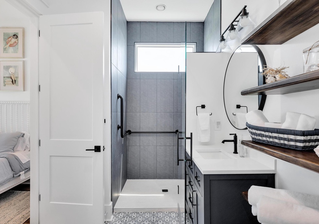 Your en-suite bathroom blends modern elegance with thoughtful design—crisp white fixtures, sleek black accents, and a spa-like walk-in shower await your morning refresh.