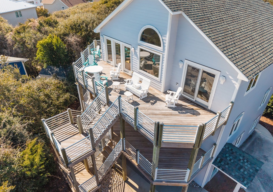 Aerial view of beach house featuring expansive multi-level deck with outdoor dining area and coastal neighborhood surroundings.