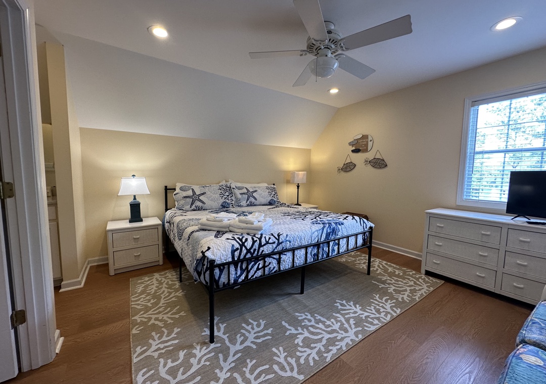 Relax in your serene bedroom with coastal charm. Soft bedding, soothing decor, and gentle ceiling fan breezes help you unwind after beach adventures.
