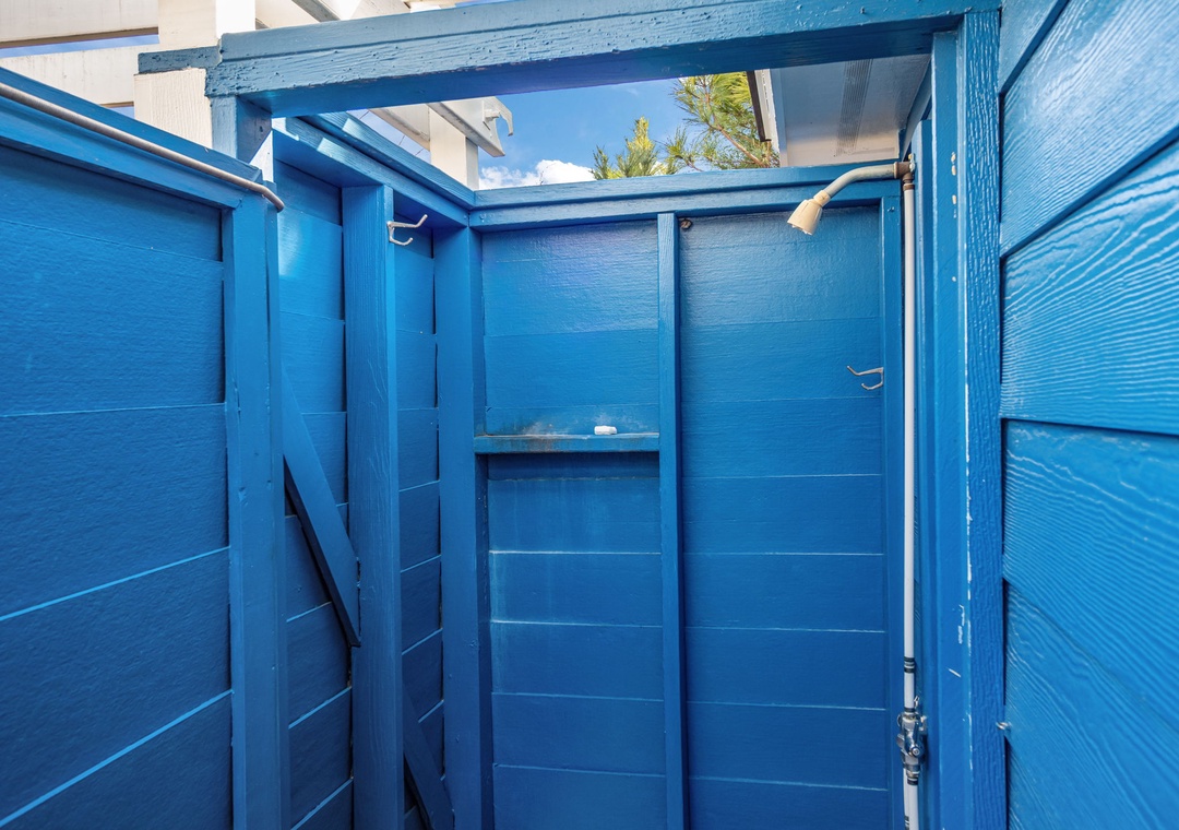 Rinse off after beach days in your private outdoor shower, surrounded by cheerful blue walls with open sky above.