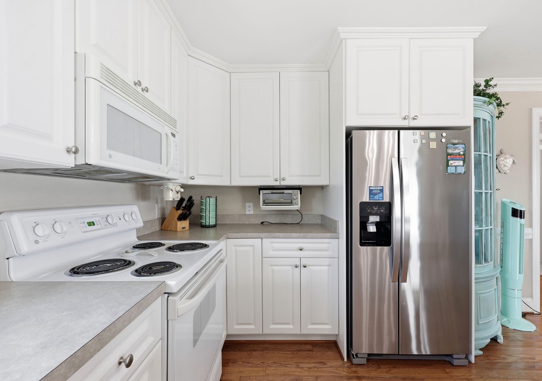 Your fully equipped kitchen features stainless steel appliances and bright white cabinetry, making meal prep feel effortless and welcoming.
