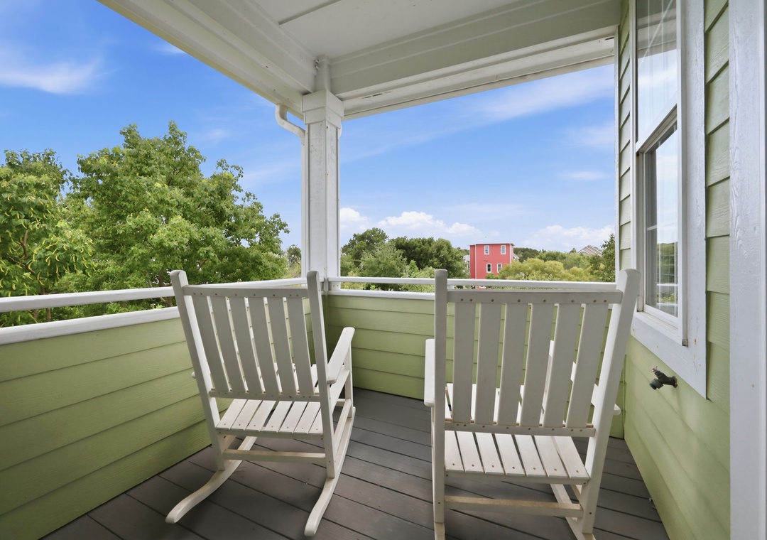 Settle into your private covered balcony with rocking chairs, where leafy treetops and blue skies create a peaceful retreat to sip morning coffee or unwind after exploring the area.