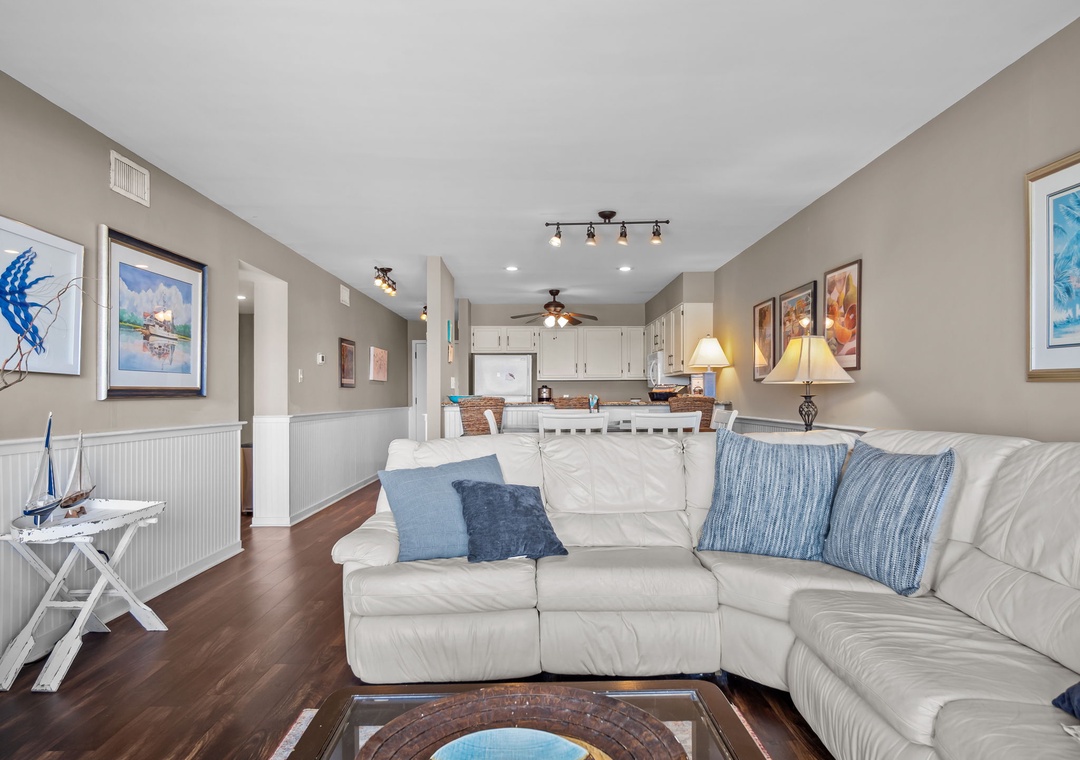 Sink into plush leather seating in your open-concept living space, where coastal artwork and warm lighting create the perfect atmosphere for relaxation.