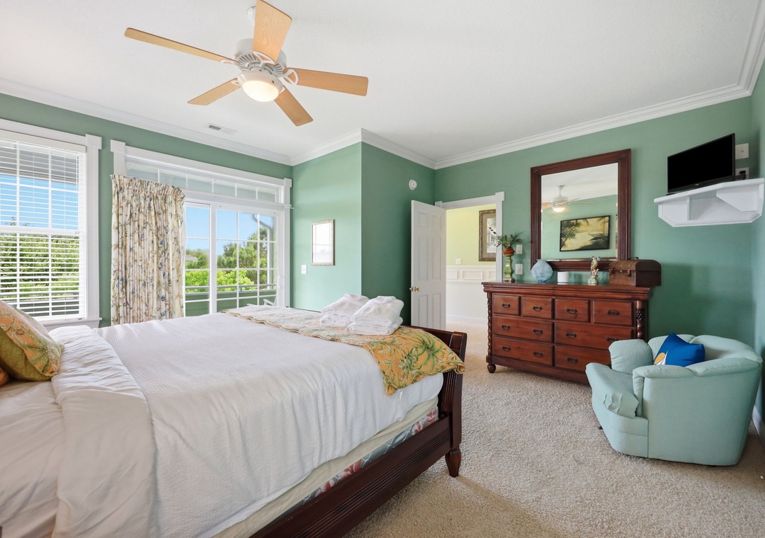 Unwind in your peaceful bedroom with soothing sage-green walls, a plush king bed, and a cozy chair. Large windows invite natural light and tropical breezes from your private balcony.