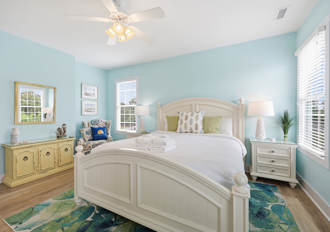 Drift off to sleep in this peaceful coastal bedroom, where soft aqua walls and crisp white linens invite you to unwind. The ceiling fan keeps things cool and comfortable for your stay.