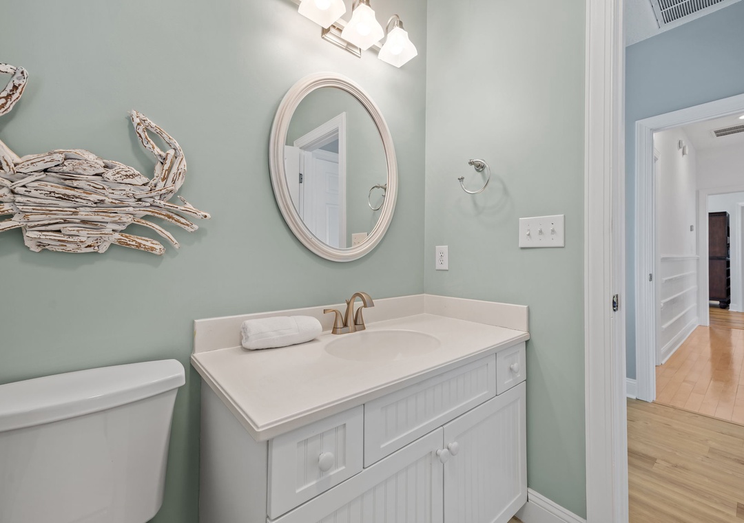 Freshen up in your coastal-inspired bathroom with calming sea-green walls, charming crab artwork, and crisp white vanity.