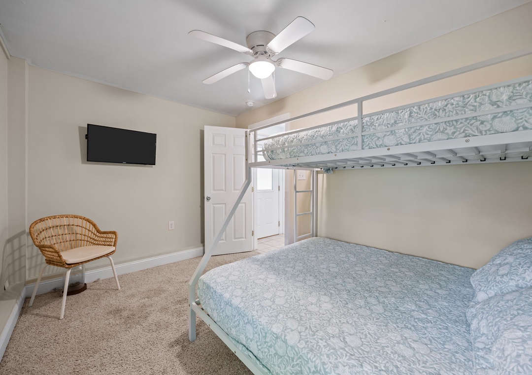 Your cozy bedroom features comfortable bunk beds with soft blue linens, a ceiling fan for cool nights, and modern amenities like a wall-mounted TV.