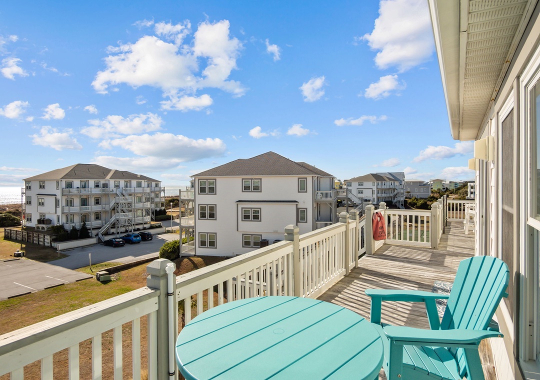 Relax on your private balcony with turquoise furniture, enjoying neighborhood views and fresh ocean air under beautiful blue skies.