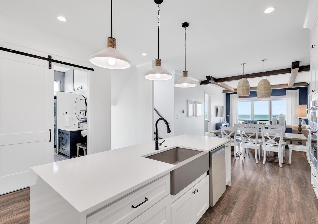 Bright coastal kitchen opens to dining with sea views, inviting you to cook and gather where beach breezes meet modern comfort.