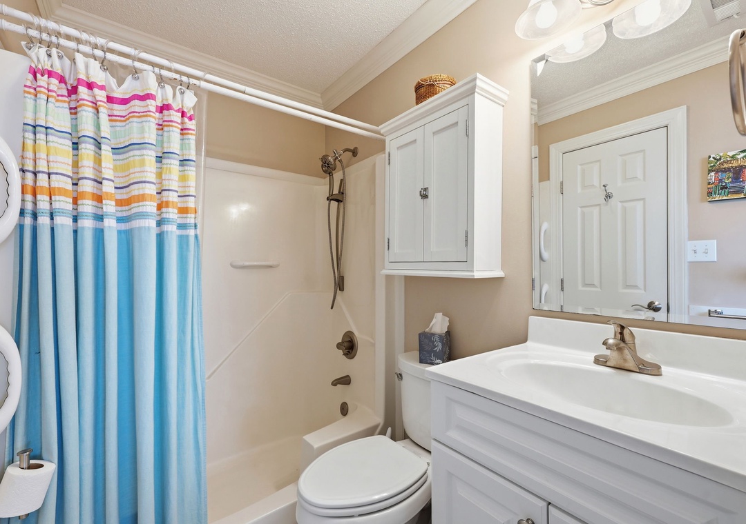 Freshen up in your private bathroom with a full tub-shower combo, crisp white cabinetry, and plenty of storage for your essentials—perfect for unwinding after a day of adventure.