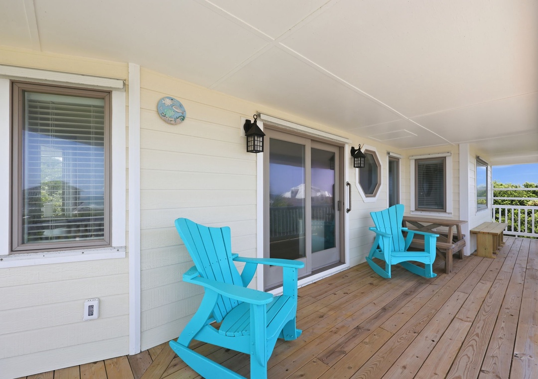 Imagine yourself unwinding here—bright turquoise chairs invite you to settle in, ocean breeze in hand, as natural light spills across the welcoming deck where relaxation meets coastal charm.