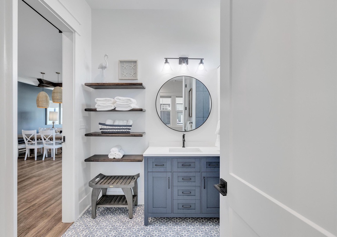 Refresh in your stylish bathroom, where coastal-inspired blue cabinetry, warm wood shelving stocked with fresh towels, and modern fixtures create a serene retreat after a day of adventure.