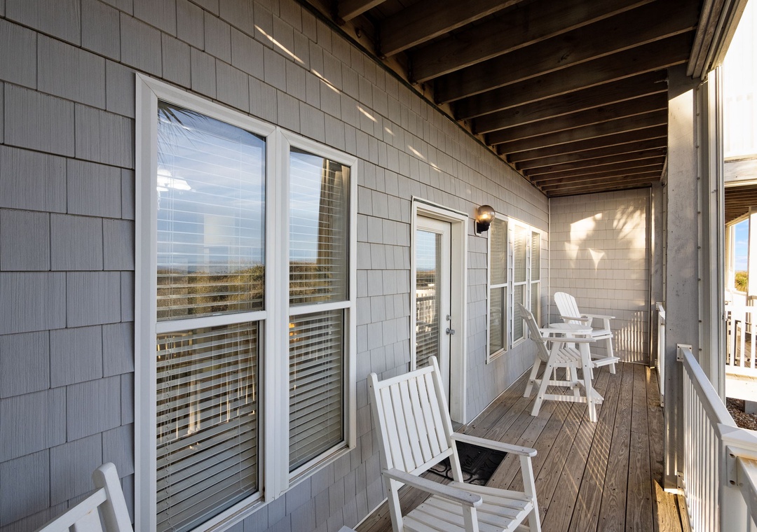Step onto your private covered balcony where white rocking chairs invite you to unwind while gentle breezes carry ocean whispers through the afternoon light.