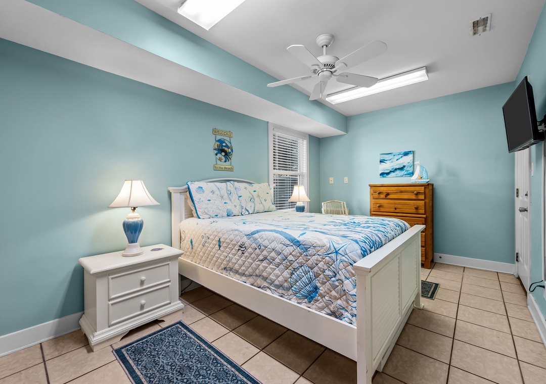 Unwind in your coastal-themed bedroom with aqua walls, ceiling fan breeze, and ocean-inspired linens creating a peaceful retreat.