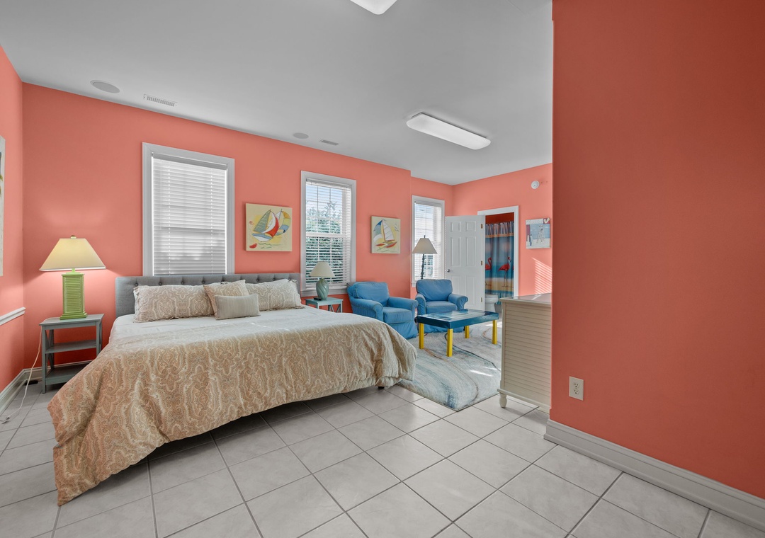 Wake up in your vibrant coral-themed bedroom with comfortable bedding and cozy seating area perfect for relaxing.