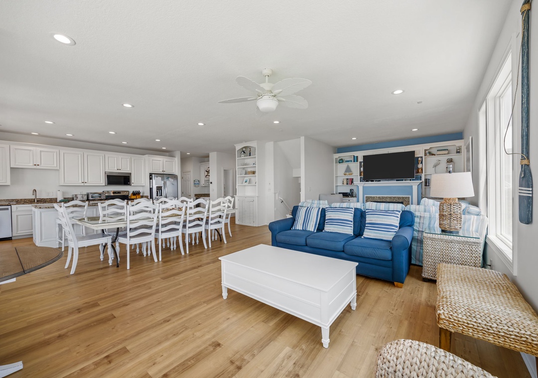 You'll love this bright open-concept space where gleaming white kitchen flows into comfortable living room with coastal blue sofa and dining for eight.