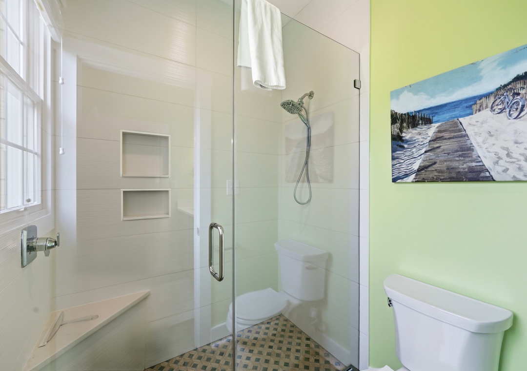 Your bright, clean bathroom features a walk-in shower with crisp white tile, built-in niche storage, and a cheerful coastal-inspired ambiance for refreshing mornings.
