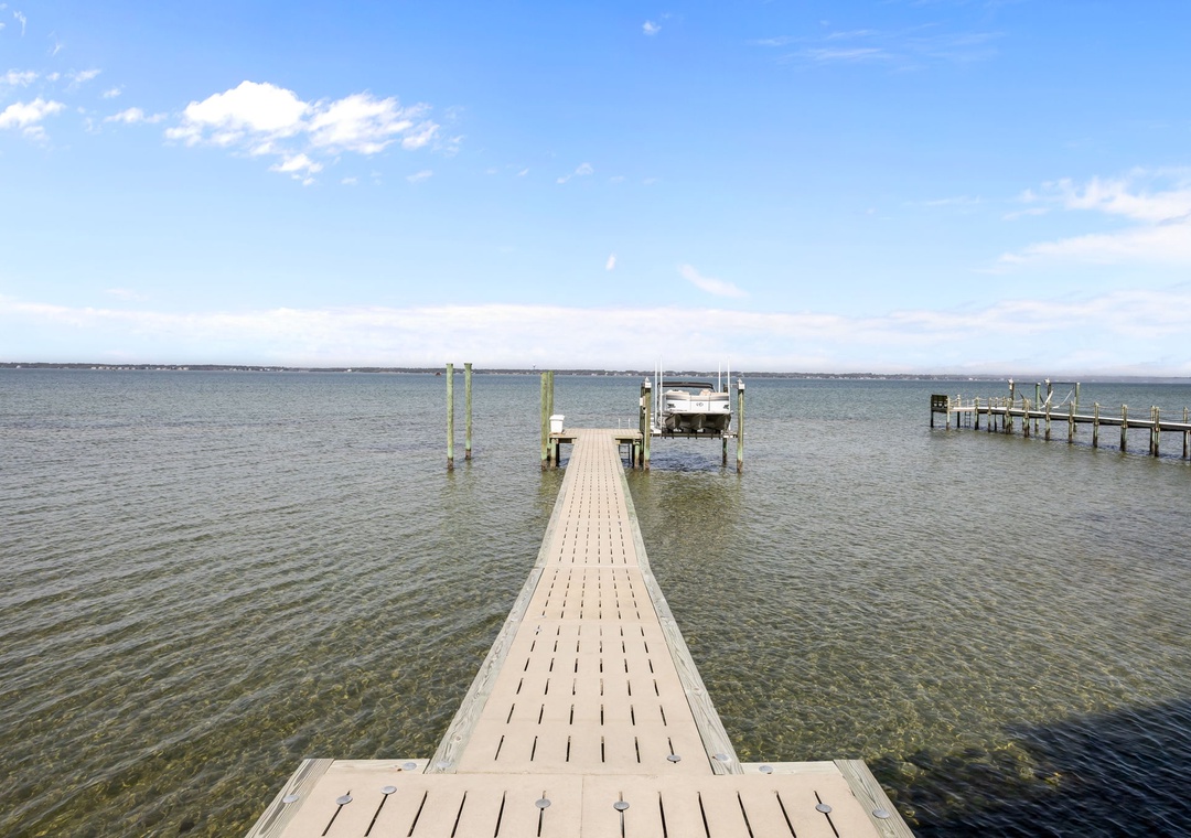Wooden dock extends into calm waters under blue skies, providing peaceful lakeside access in the surrounding area.