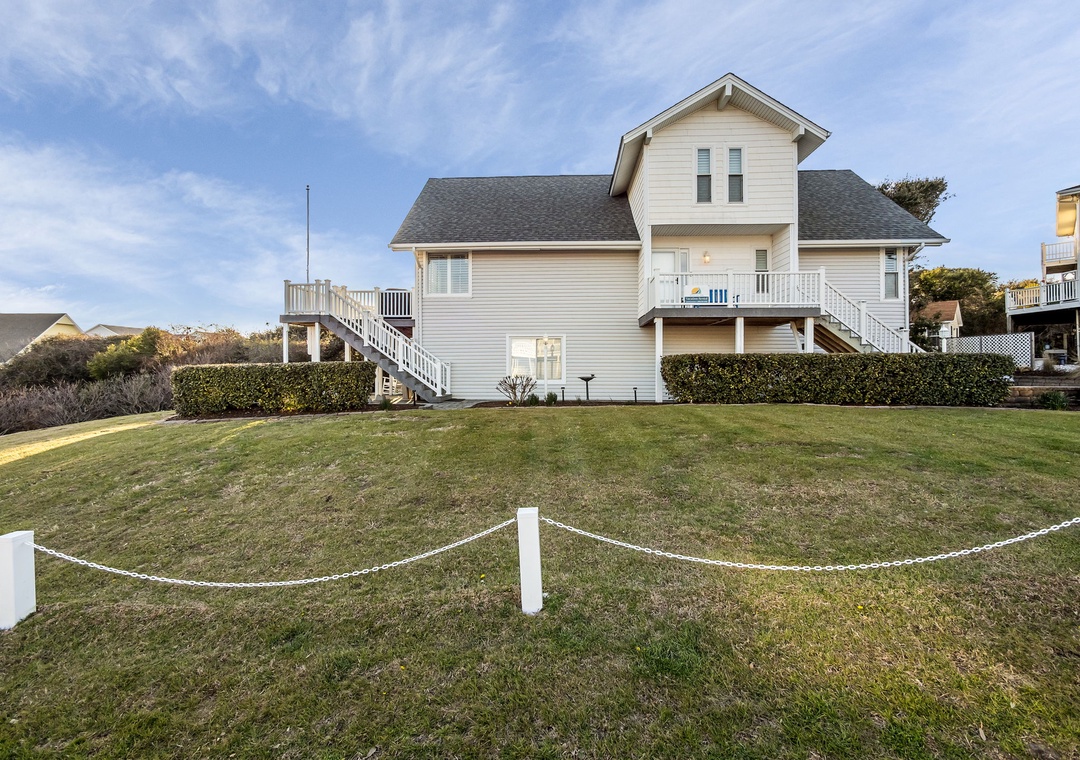 Charming coastal home with spacious lawn and private elevated deck surrounded by peaceful residential neighborhood.