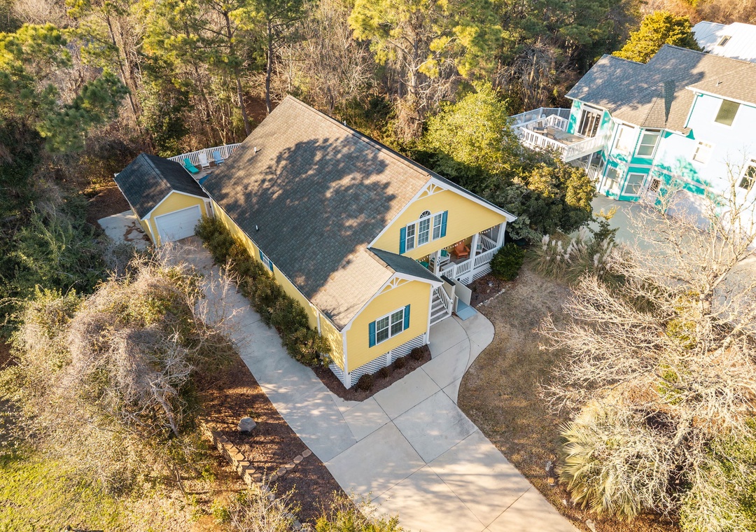 Charming yellow cottage nestled among trees with private driveway and peaceful wooded surroundings.