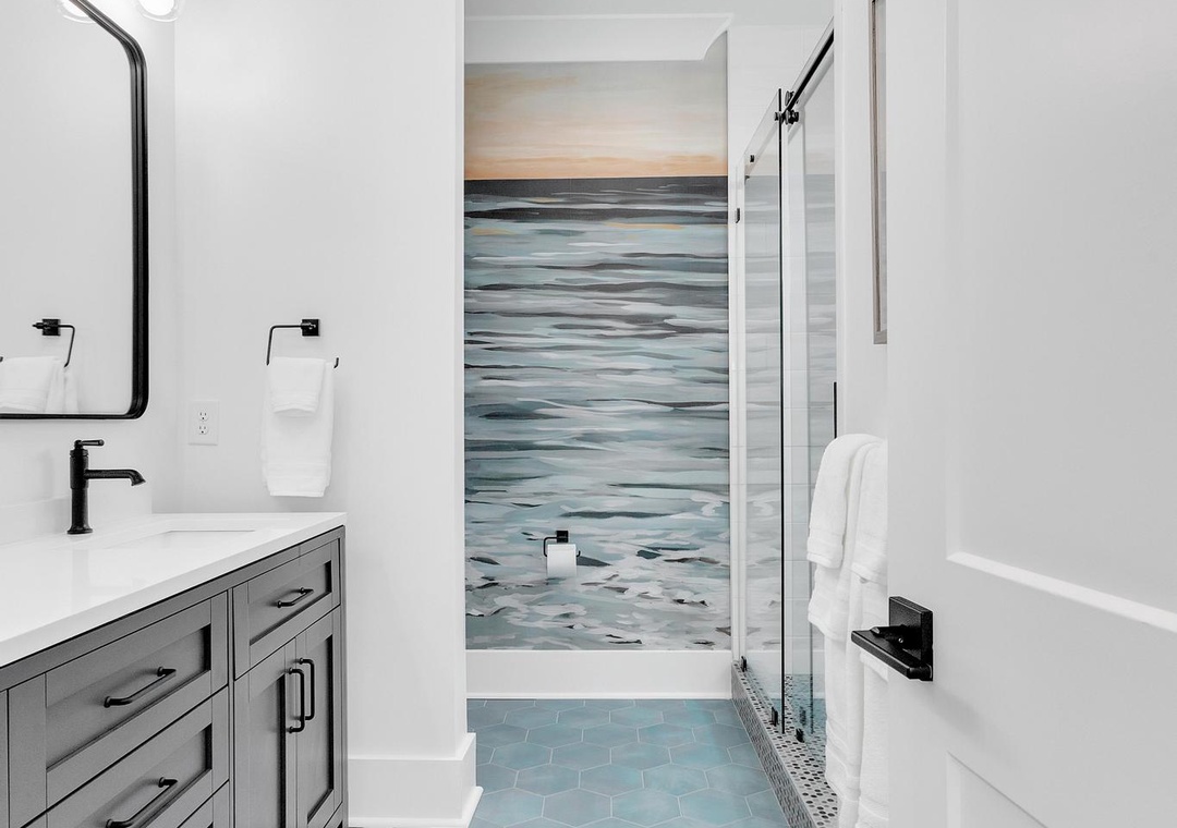 Refresh in this serene coastal-inspired bathroom where soft blues and calming ocean-inspired tiles invite relaxation after a day exploring the area.