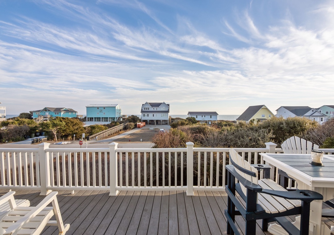 A scenic coastal neighborhood with colorful beach houses stretches beyond this charming outdoor deck area.