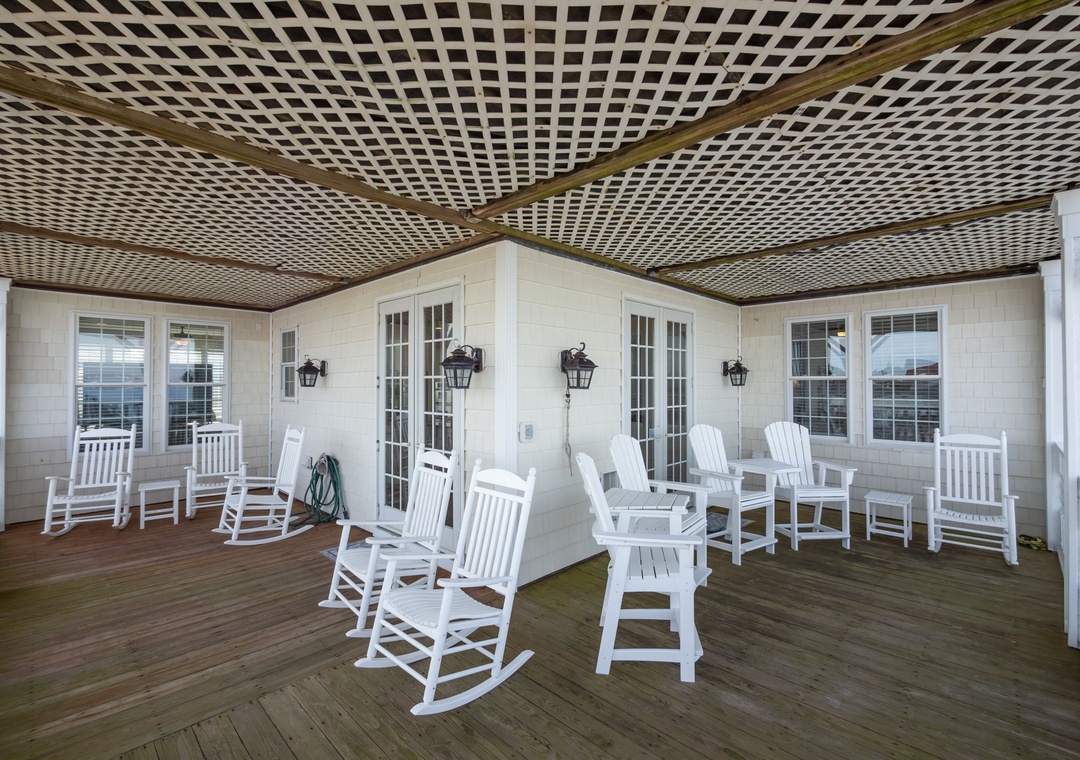 Your spacious covered porch invites you to unwind in classic white rockers, where gentle breezes and peaceful moments await under the charming lattice ceiling.