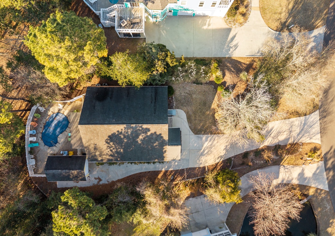 Aerial view of the property showcasing the main building, swimming pool, and beautifully landscaped grounds surrounded by mature trees.