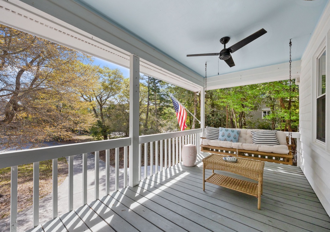 Relax on your private covered porch with ceiling fan and cozy seating, overlooking peaceful neighborhood trees.